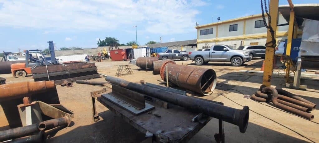 Acopio de tuberías, vigas y perfiles metálicos en patio de logística industrial