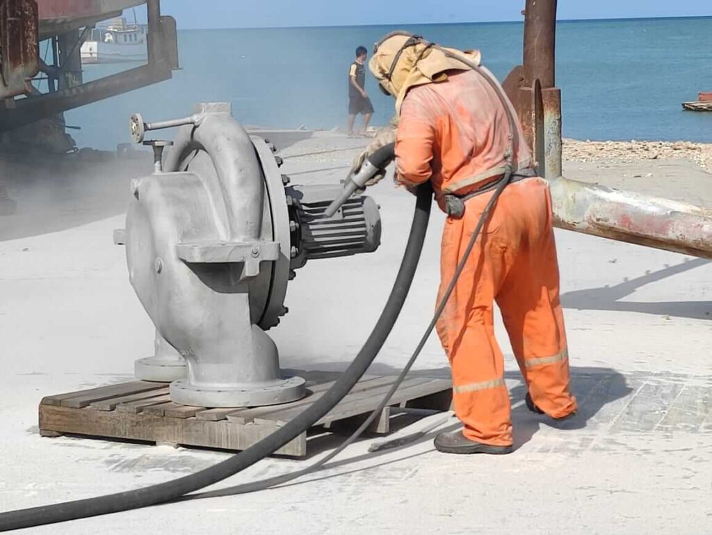 Operario ejecutando chorreado abrasivo (sandblasting) en equipo rotativo pesado